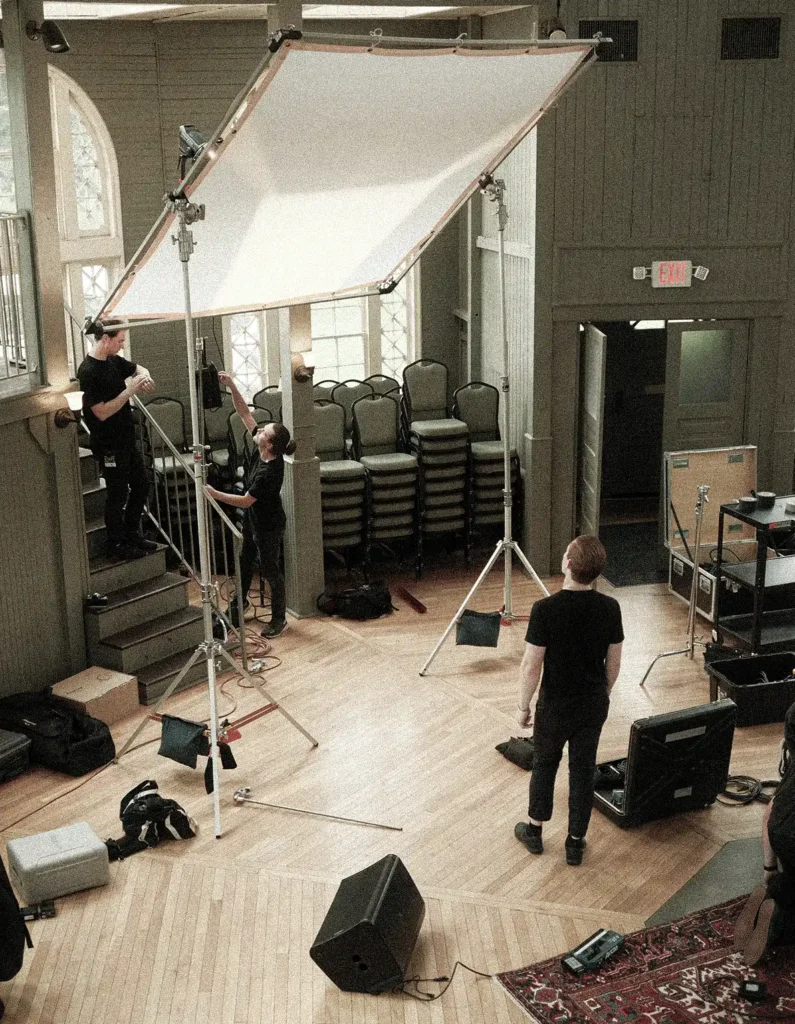 equipo de producción audiovisual montando iluminación en un rodaje profesional