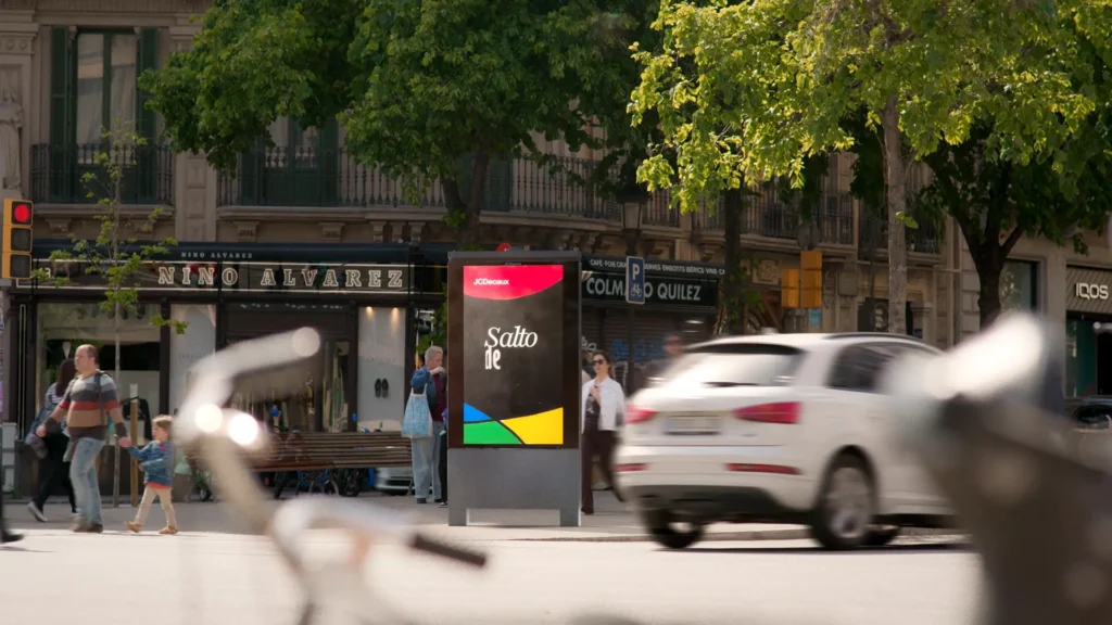 Coche circulando junto a un MUPI integrado en 3D en una calle de Barcelona
